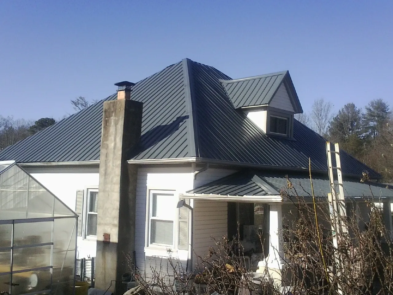 Dark blue standing seam metal roof on a white farmhouse with dormer — Slate & Tile Roof Repair by Roofing Brothers in Floyd