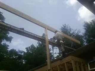 Carpenter setting a ridge beam over a new addition frame — Ice Dam Removal by Roofing Brothers in Floyd