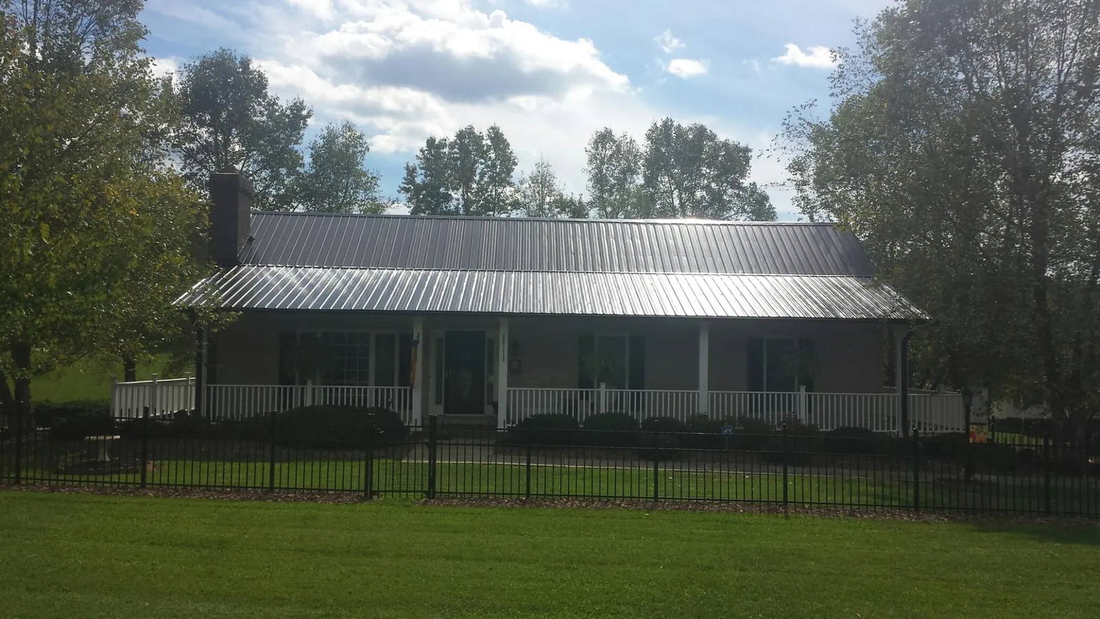 Gray metal roof on a brick ranch with a full width front porch — Gutter Guard Installation work by our crew in Floyd