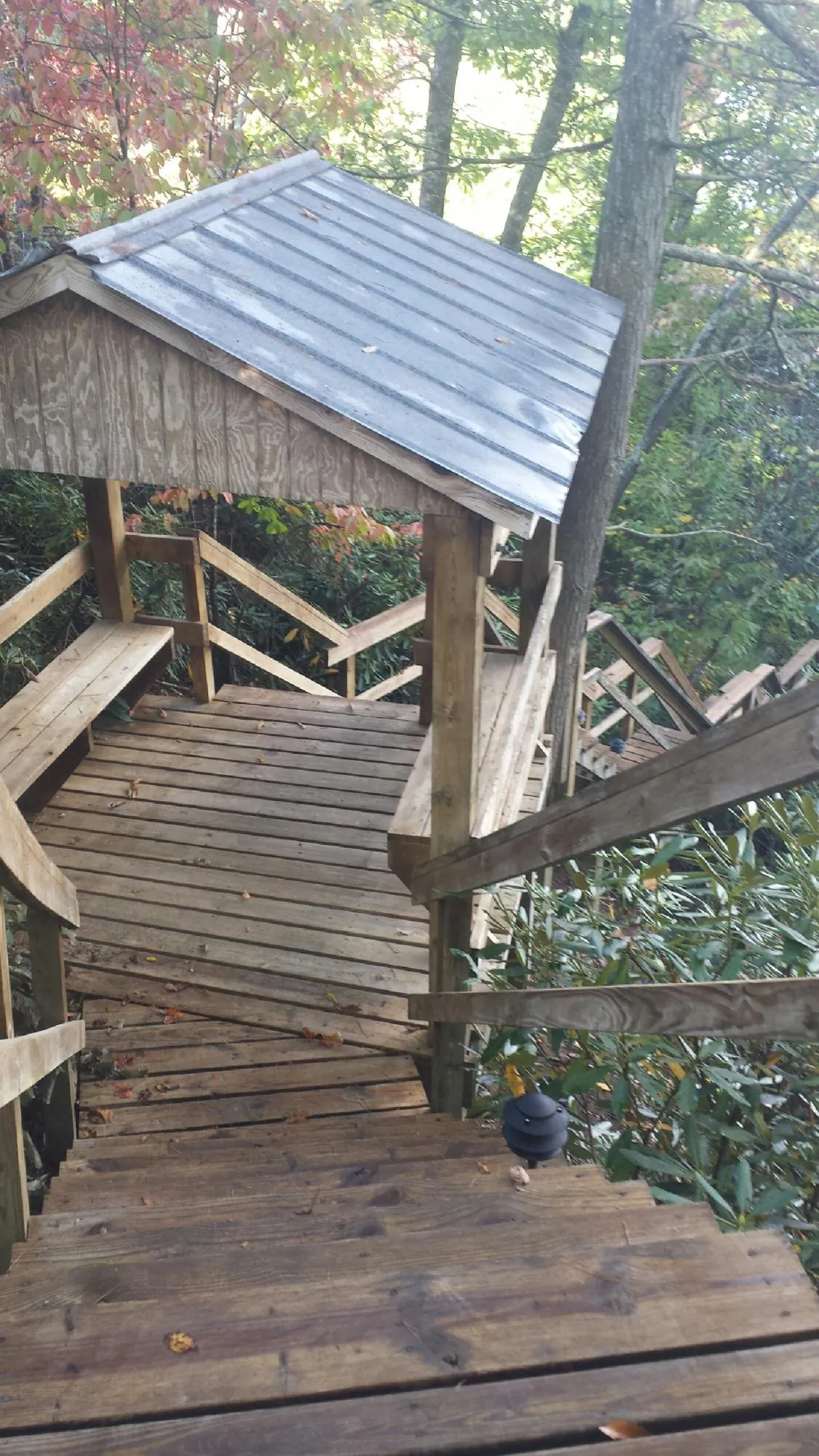 Metal roofed shelter over wooden steps on a wooded walkway — Skylight Repair & Installation work by our crew in Floyd