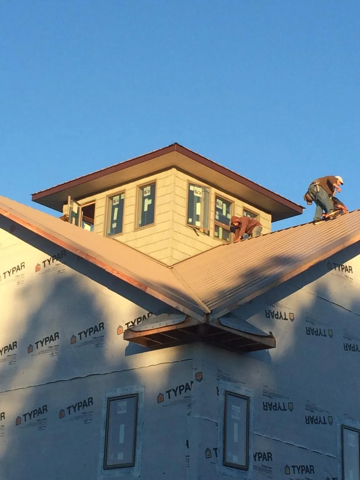 Roofers working around a rooftop cupola on a new metal roof at sunset — Roof Waterproofing in Floyd by Roofing Brothers
